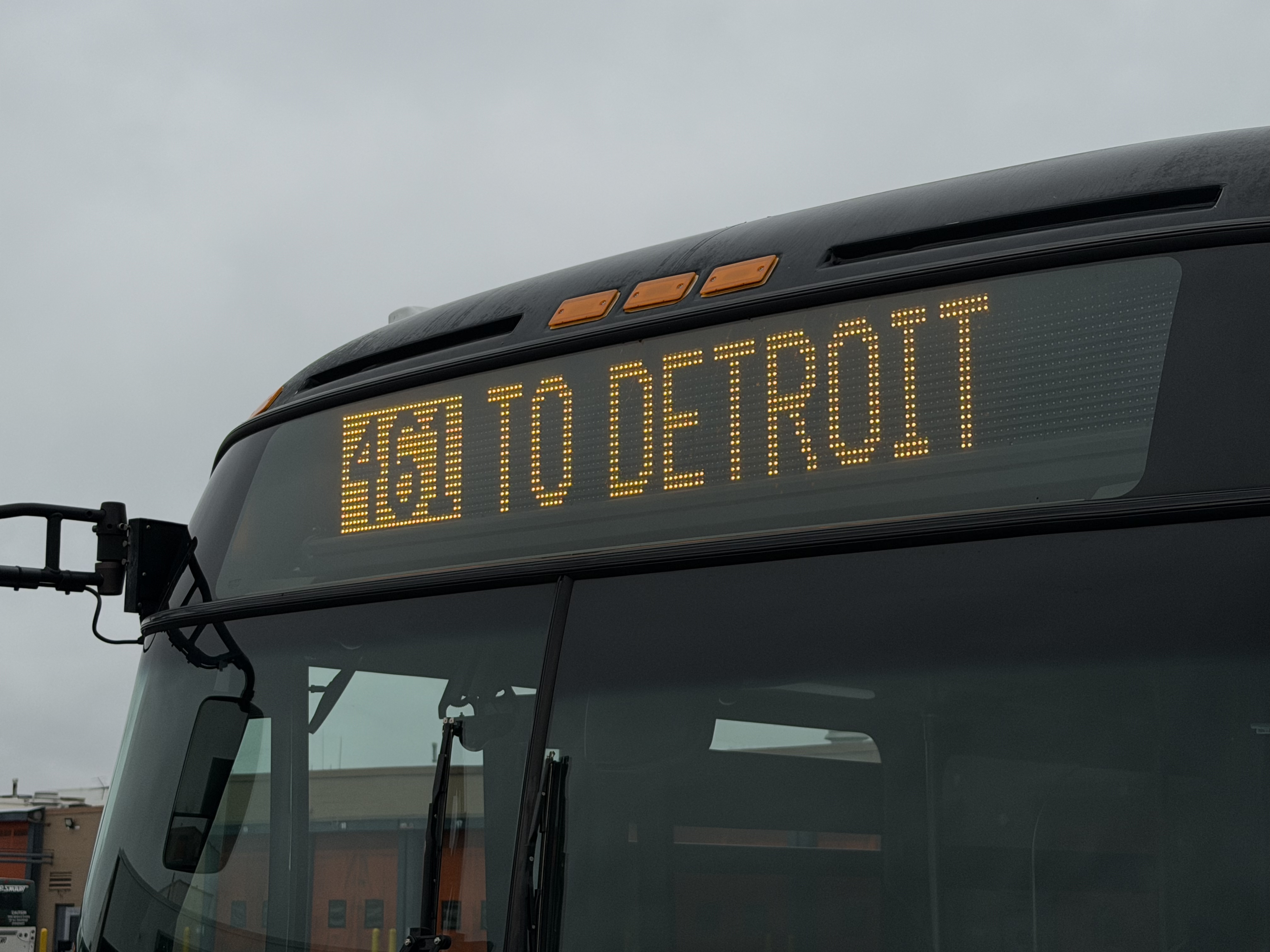 A bus displays "461 TO DETROIT" with the route number in an orange box A bus displays "461 TO DETROIT" with the route number in an orange box